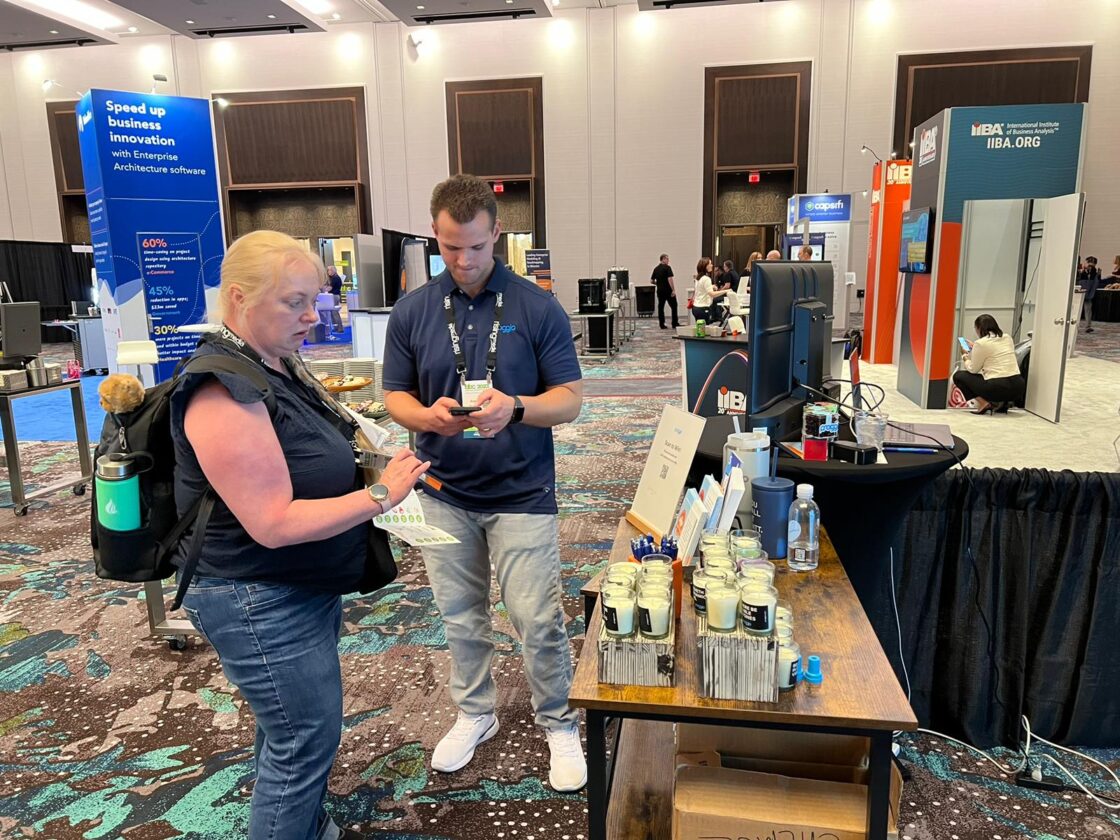 Two people standing at a booth with products in a conference hall.