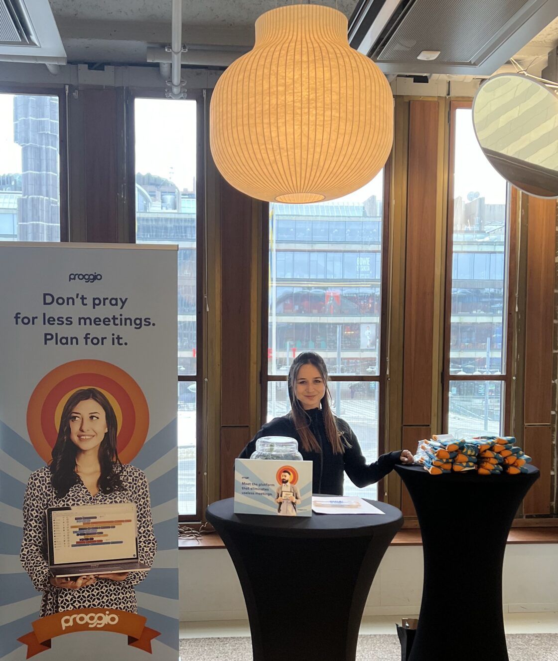 A woman stands at a booth with a sign that reads, "Don't pray for less meetings. Plan for it.