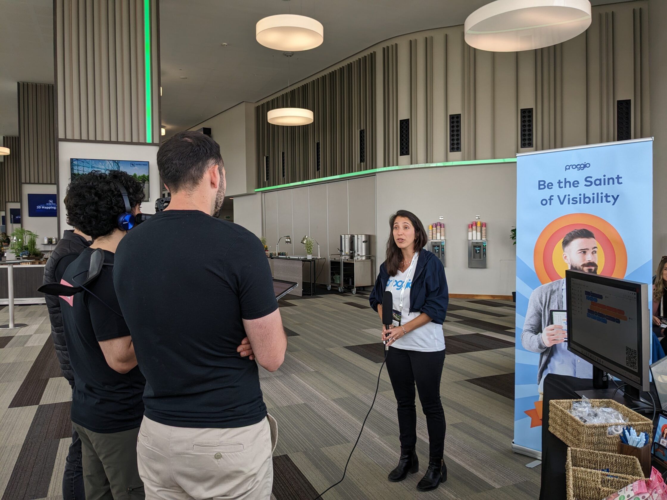 Person being interviewed at a trade show in front of a booth display.