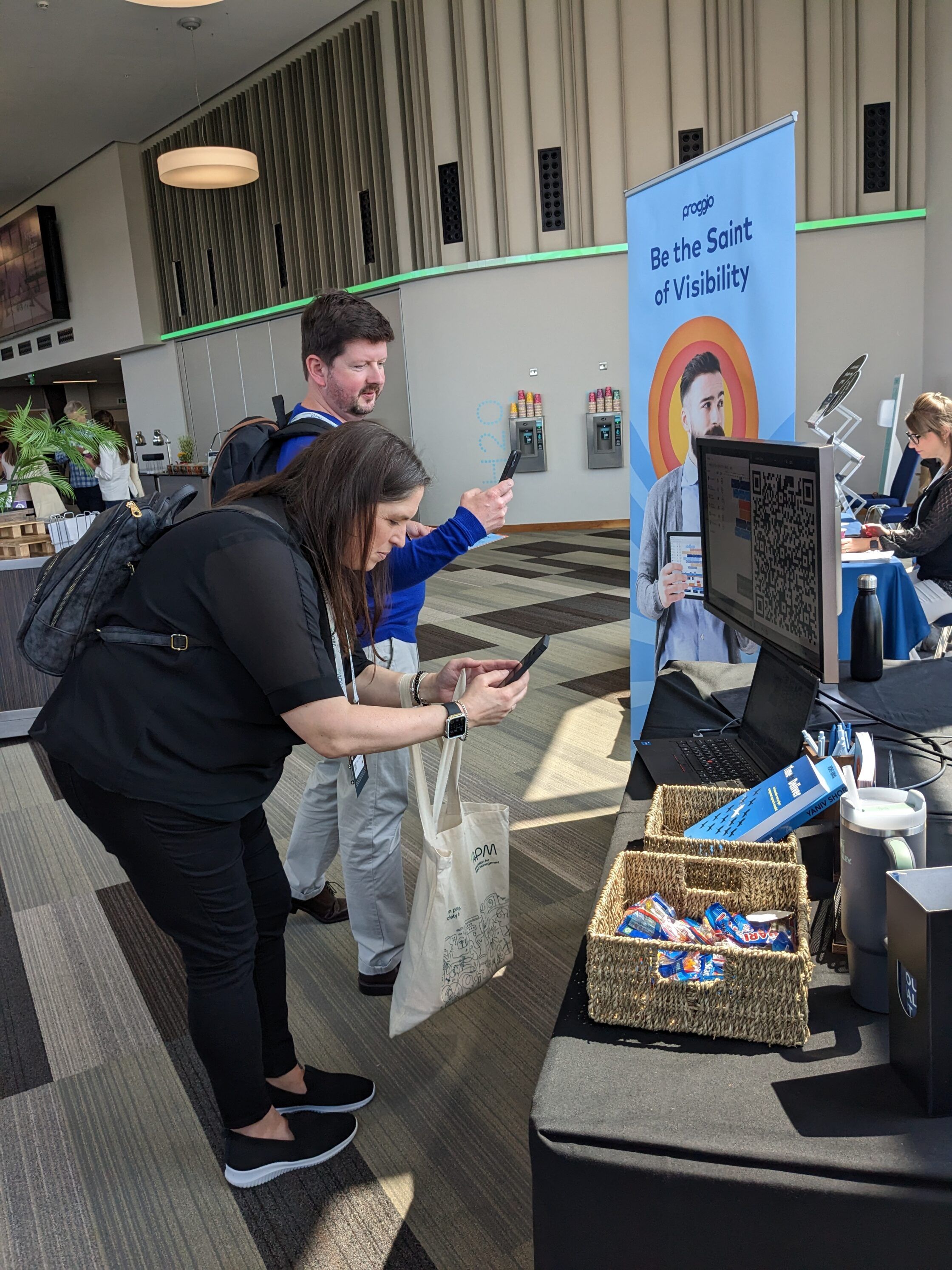 People at a conference booth scanning a QR code with phones.