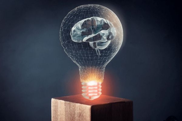 A brain inside a lightbulb on a wooden base, symbolizing innovation and intellect.